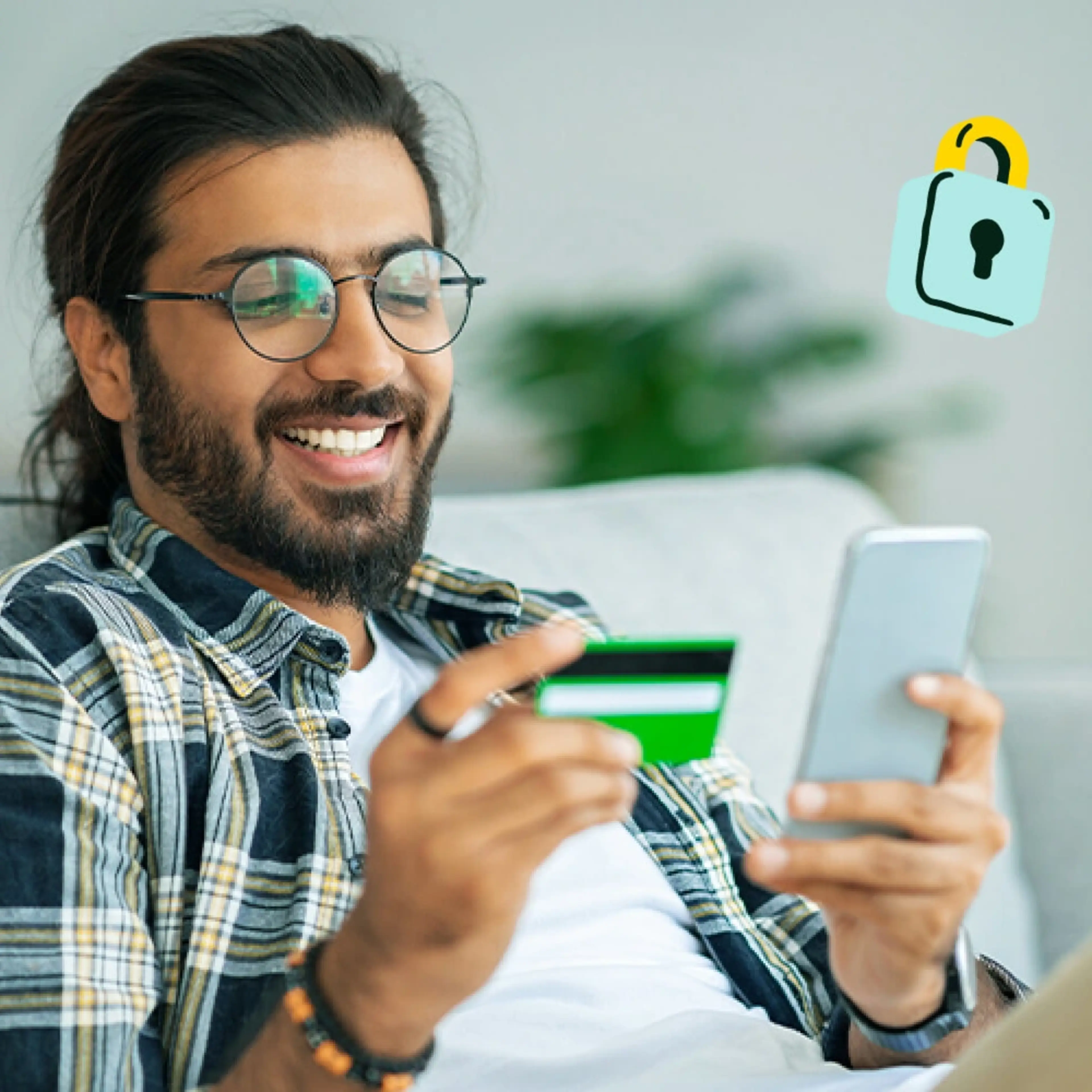 A man sits on the couch and uses his secured credit card.