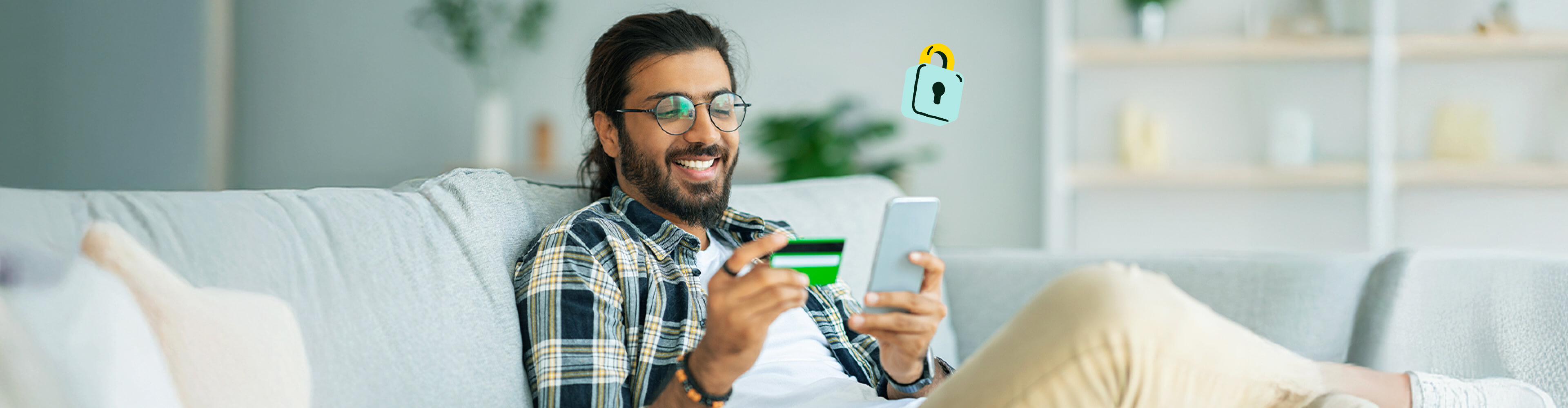 A man sits on the couch and uses his secured credit card.