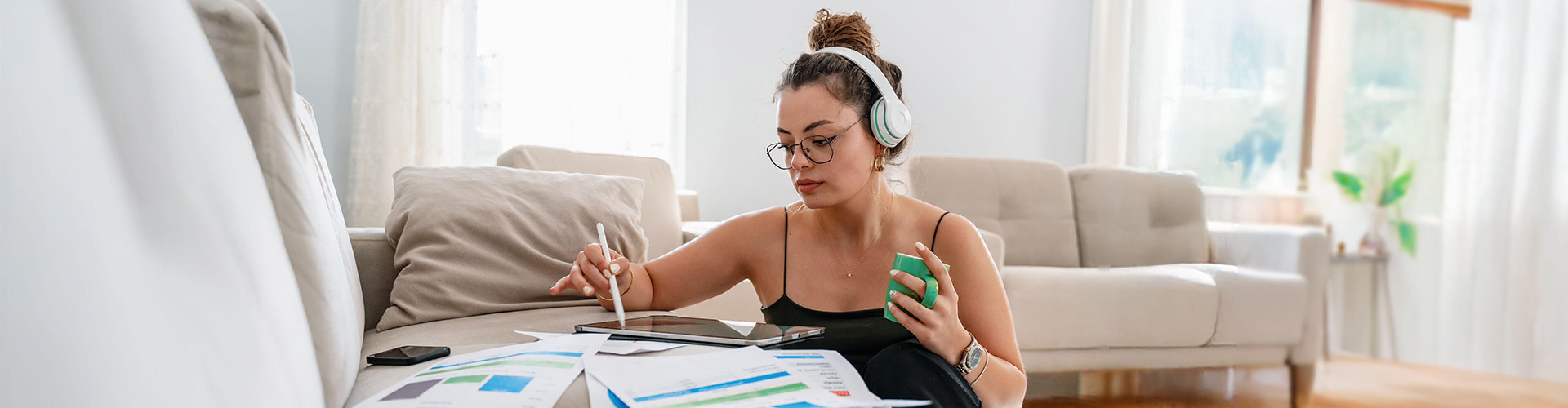 A woman creating a budget while listening to a finance podcast.